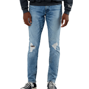 Light blue distressed jeans with ripped knee details, paired with black high-top sneakers and a dark sweatshirt.