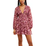 A floral long-sleeve mini dress with a deep V-neck and shirred waist, featuring a purple background and pink flower pattern.