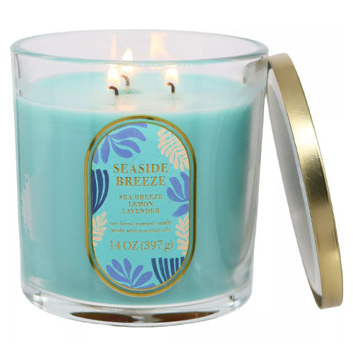 A blue scented candle labeled \“Seaside Breeze\“ with scents of sea breeze, lemon, and lavender, in a 14 oz (397 g) glass container with a gold-edged lid.