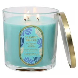 A blue scented candle labeled \“Seaside Breeze\“ with scents of sea breeze, lemon, and lavender, in a 14 oz (397 g) glass container with a gold-edged lid.