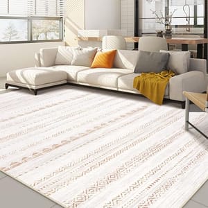 A washable rug featuring a white base with geometric patterns in shades of brown and orange, placed in a living room with a sectional sofa and wooden furniture.