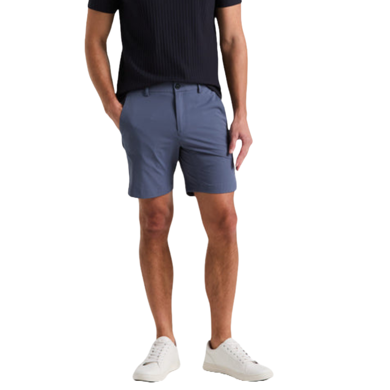 The Stretch Solid Tech Short is a pair of sleek, blue shorts with a tailored fit, featuring belt loops and side pockets, paired with a navy ribbed shirt and white sneakers.
