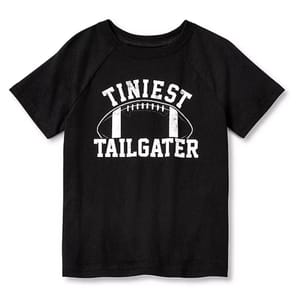 Black T-shirt with white text and a football graphic, reading \“Tiniest Tailgater.\“