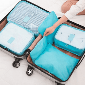 A suitcase is organized with blue packing cubes, containing folded clothes for efficient travel storage.