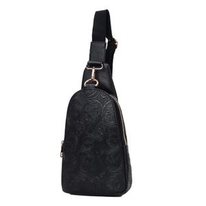 A black crossbody sling bag with embossed floral patterns and gold-tone hardware, featuring a single adjustable strap and a side zipper.