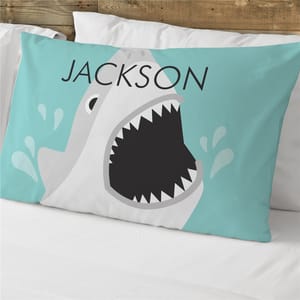 A pillowcase features a cartoon shark design with an open mouth against an aqua background, personalized with the name \“Jackson.\“