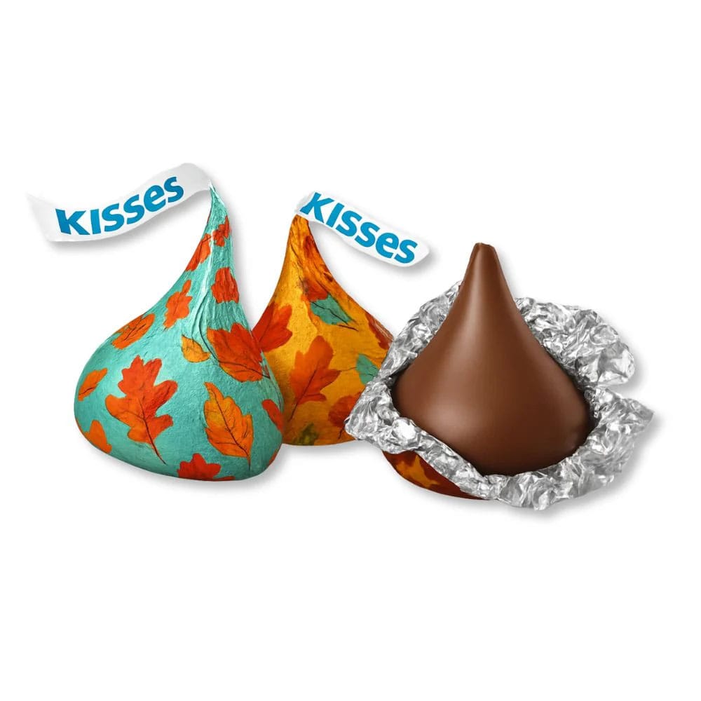 Three Hershey's Kisses are shown, two wrapped in fall-themed foil with colorful leaf designs and one unwrapped, displaying the chocolate.