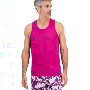 A man is wearing a magenta tank top with \“BOSS\“ text and floral-patterned shorts featuring white, pink, and dark blue colors.