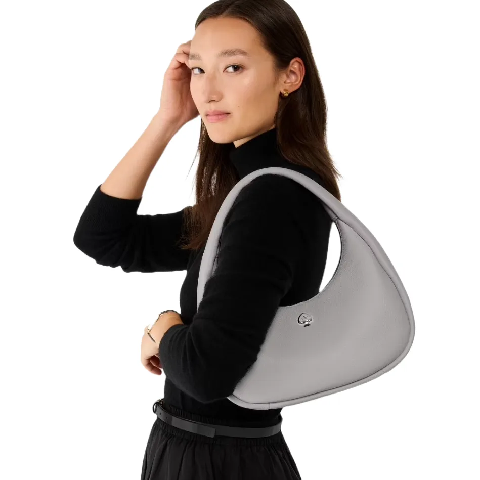 A sleek, gray leather shoulder bag with a crescent shape and a small metal logo on the front. It has a wide strap, ideal for comfortable carrying.