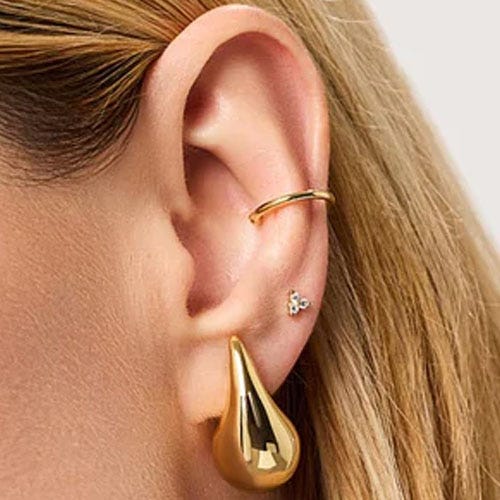 a gold teardrop-shaped earring on a person with blonde hair