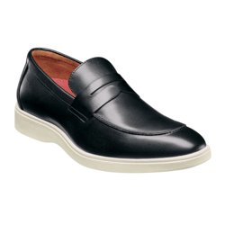 A black leather penny loafer with a white rubber sole and a red interior lining, combining classic and casual elements.