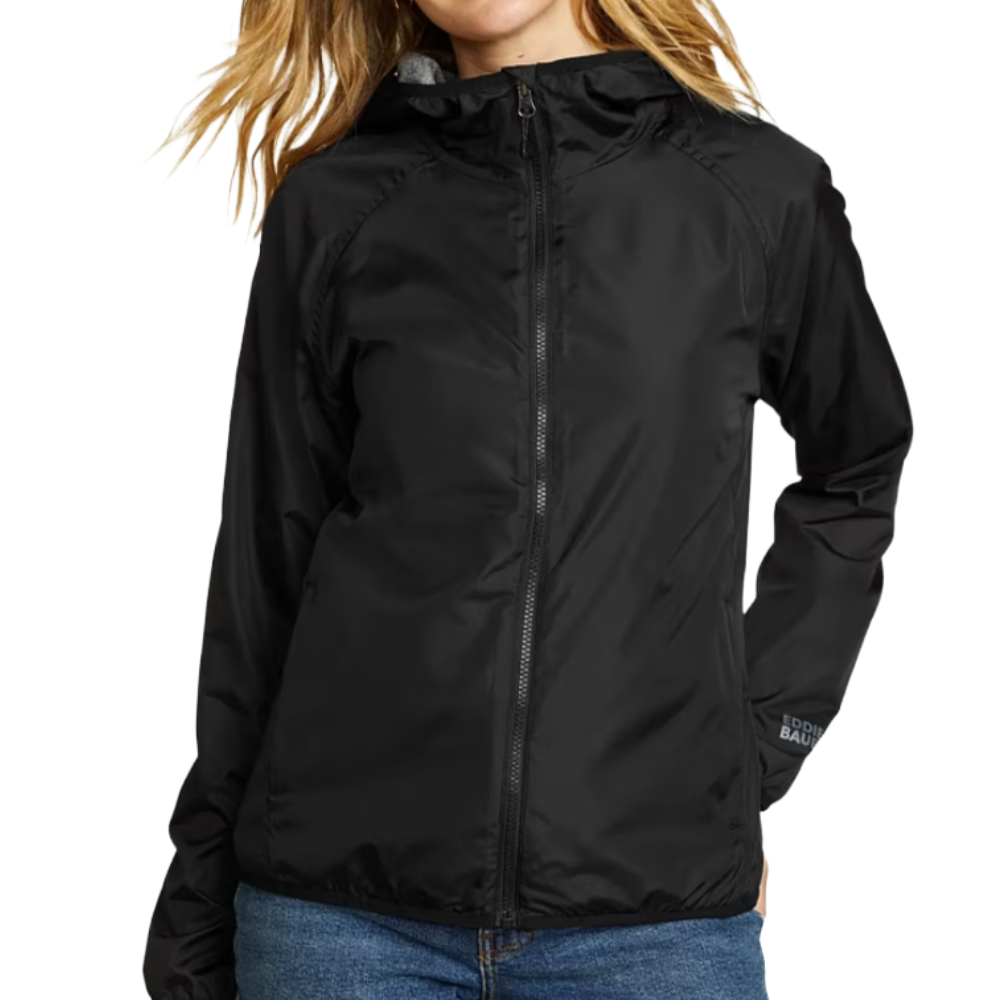 A woman is wearing a black, lightweight zip-up jacket with a hood from Eddie Bauer, paired with blue jeans.