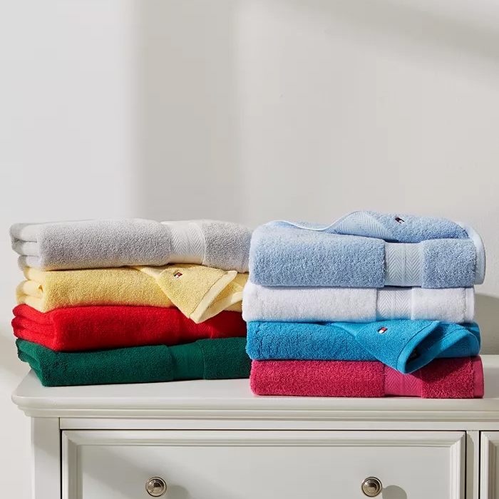 Two stacks of folded towels in various colors on a white cabinet.