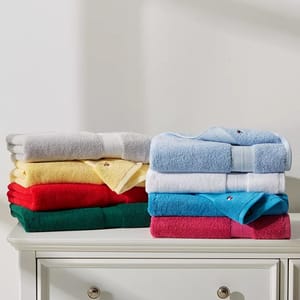 Two stacks of folded towels in various colors on a white cabinet.