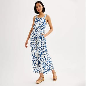 A woman modelling a blue and white sleeveless maxi dress with a tie-waist design, paired with beige wedge sandals.