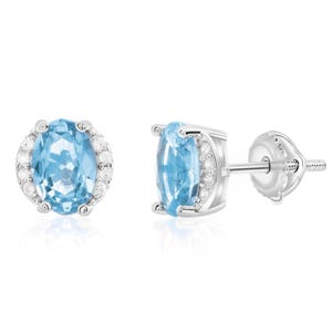 Pair of stud earrings featuring oval blue gemstones set in a silver prong setting, accented with small clear stones on the sides, and secured with screw-back posts.