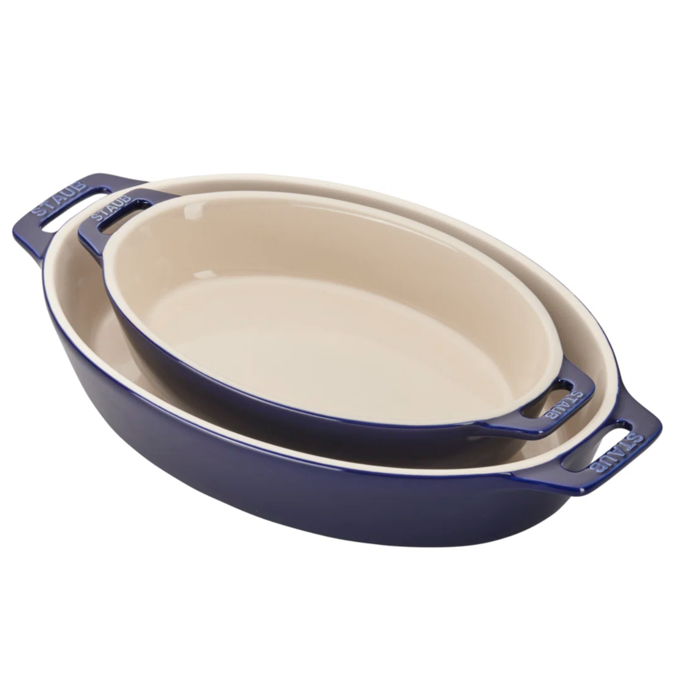 Two oval baking dishes with a blue exterior and cream interior, featuring handles labeled \“STAUB.\“ They are stacked together, with the smaller dish nested inside the larger one.