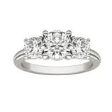 A three-stone diamond ring featuring a larger central round diamond flanked by two smaller round diamonds set in a silver band.