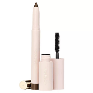 The 2pc Rare Beauty Essential Eye Duo includes a light pink eyeliner with a retractable brown tip and a matching mascara featuring a black brush. Both have \“Rare Beauty\“ branding on the packaging.
