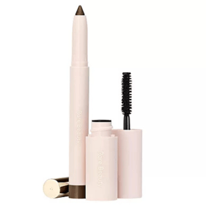 The 2pc Rare Beauty Essential Eye Duo includes a light pink eyeliner with a retractable brown tip and a matching mascara featuring a black brush. Both have \“Rare Beauty\“ branding on the packaging.
