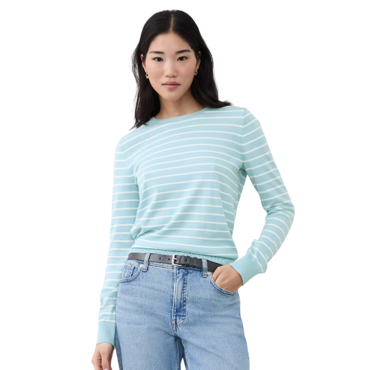A woman wearing a light blue and white striped long-sleeve shirt paired with light blue jeans and a black belt.