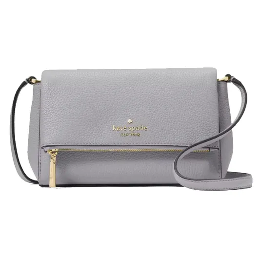 A light gray Kate Spade New York crossbody bag with a pebbled leather texture, featuring a gold logo, a front zipper pocket, and an adjustable strap.