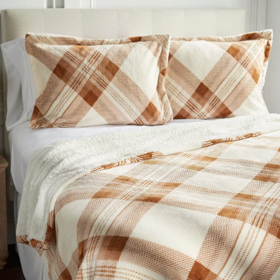 A bed set featuring a plaid pattern in beige and brown, including a blanket and two matching pillowcases.