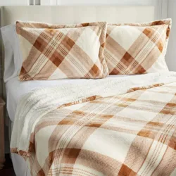 A bed set featuring a plaid pattern in beige and brown, including a blanket and two matching pillowcases.