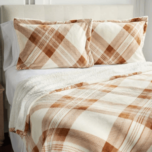 A bed set featuring a plaid pattern in beige and brown, including a blanket and two matching pillowcases.