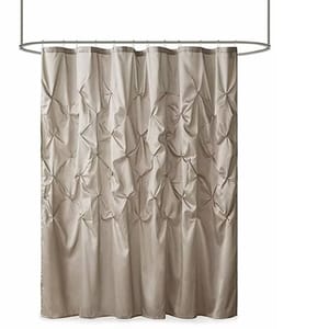 A taupe shower curtain with a textured pleated design featuring decorative diamond-shaped patterns, hanging from a curved shower rod.