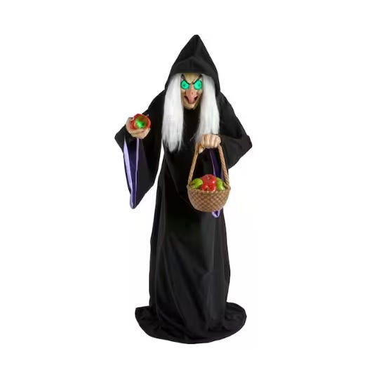 A witch figure dressed in a black cloak with white hair and glowing eyes holds a red apple and a basket of apples.