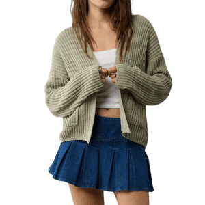 The American Eagle Open Front Cardigan is a cozy, light olive-green knit with a loose fit and long sleeves. It’s paired with a white cropped top and a blue pleated mini skirt, offering a casual, layered look.