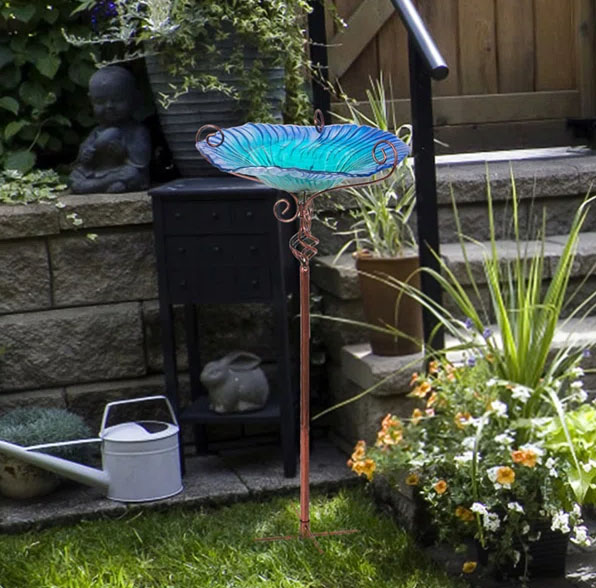 The Canora Grey Glass Bird Bath features a blue glass bowl with decorative swirls on a tall, slender metal stand, designed for garden use.