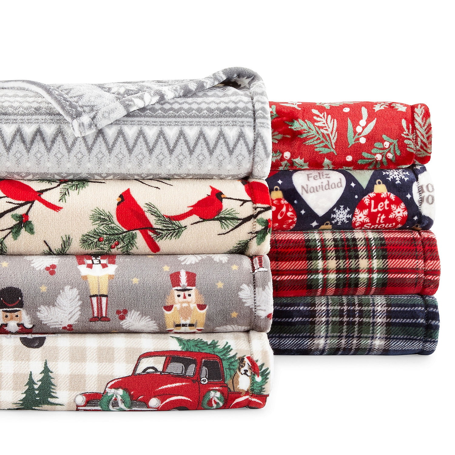 Stacked holiday-themed fleece blankets with patterns such as cardinals, snowflakes, and Christmas ornaments.