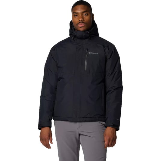 A man wearing a black Columbia hooded jacket and light gray pants.