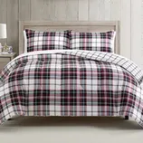Plaid comforter and pillow shams on a wooden bed frame, featuring a white, black, and red check pattern.