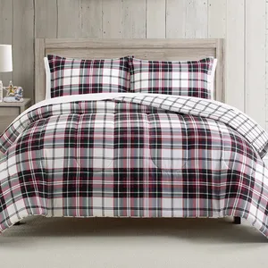Plaid comforter and pillow shams on a wooden bed frame, featuring a white, black, and red check pattern.