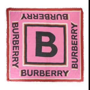Pink square scarf featuring a large central \“B\“ with \“BURBERRY\“ repeated along the borders in black, accented with a red and white trim.