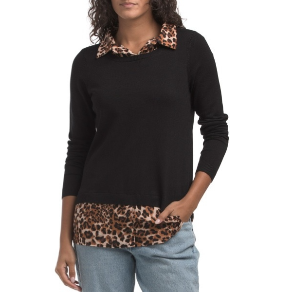 A woman is wearing a black sweater with leopard print details on the collar and hem, paired with light blue jeans.