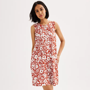 A woman is wearing a sleeveless, knee-length red and white floral dress.