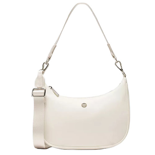 A cream-colored shoulder bag with a detachable strap, adjustable buckle, and silver hardware, featuring a small logo on the front.