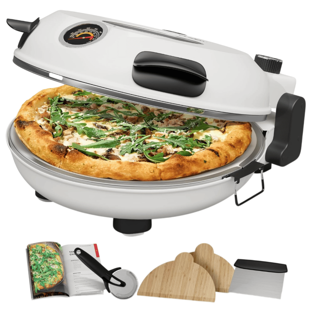 A countertop pizza oven with a pizza inside, accompanied by a cookbook, a pizza cutter, and wooden pizza peel boards.