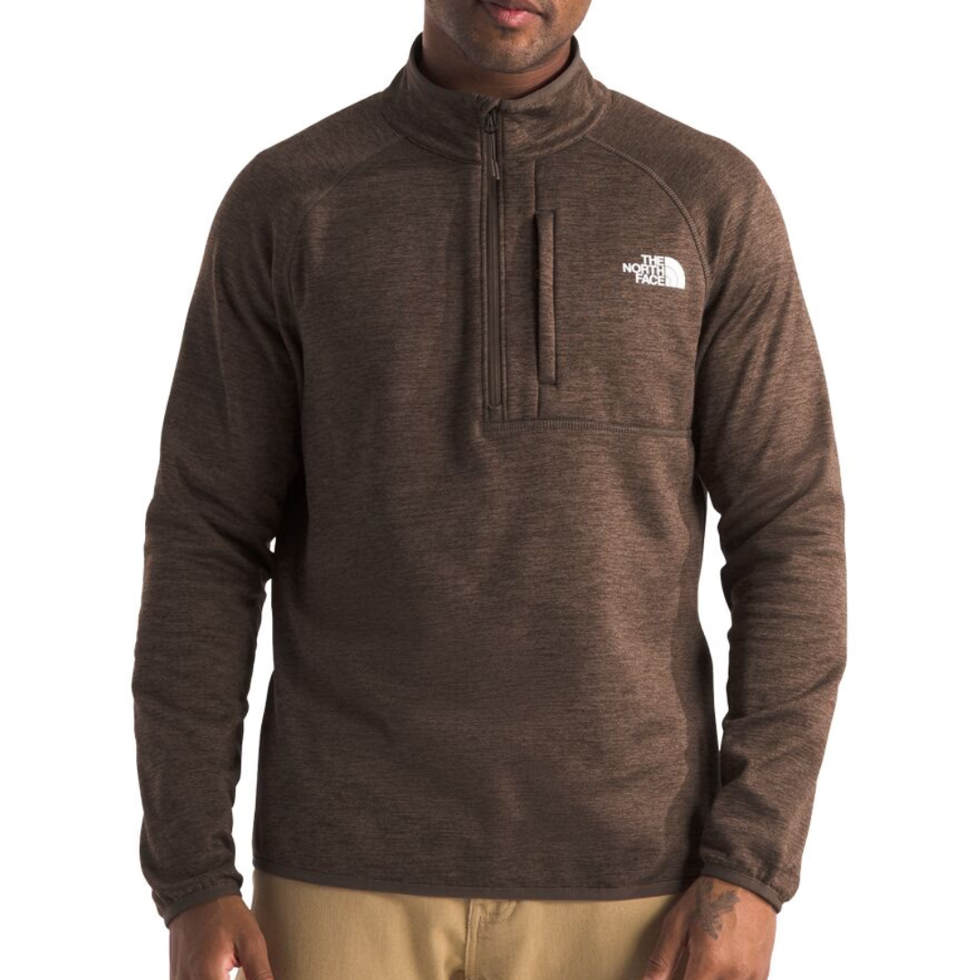 A brown quarter-zip fleece pullover with a chest pocket, featuring The North Face logo in white on the chest, paired with beige pants.