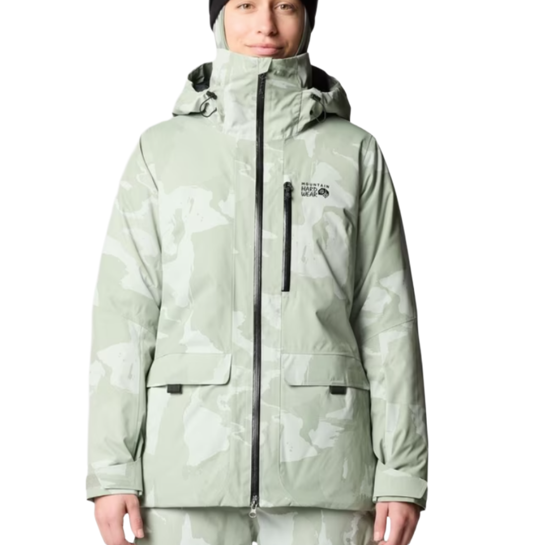 A light green and white camouflage-patterned jacket with a hood, featuring the \“Mountain Hardwear\“ logo, worn by a person with a black beanie.
