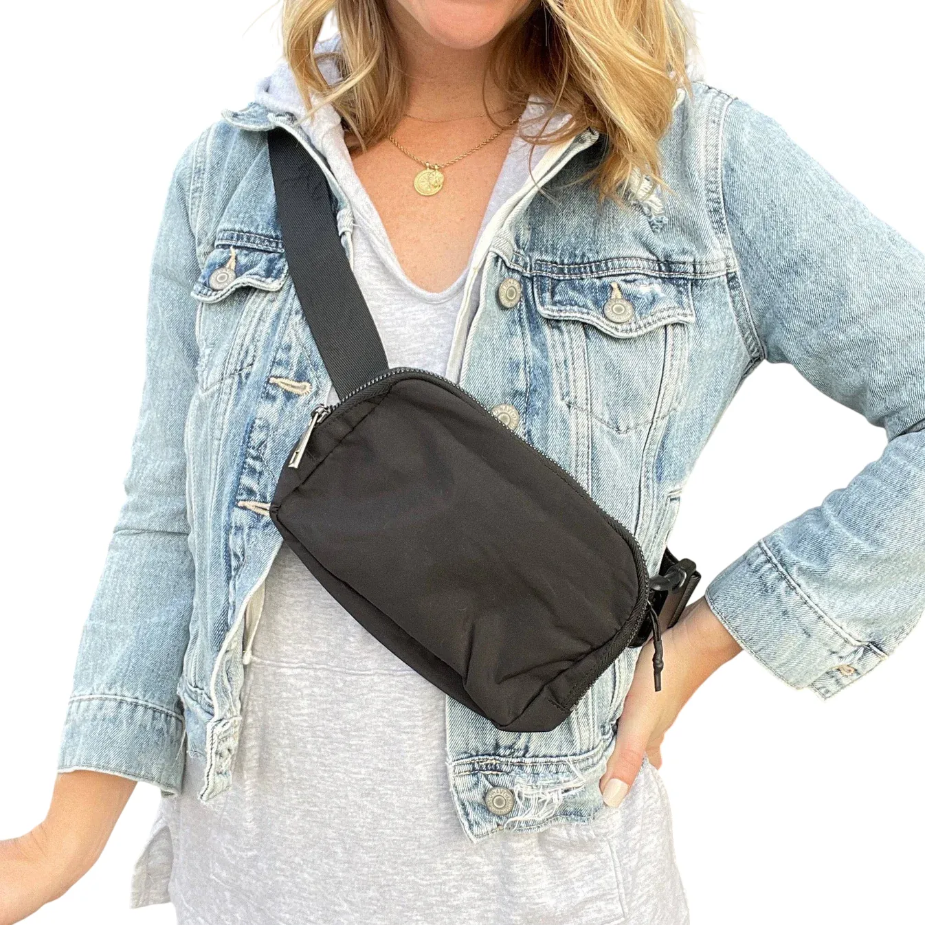 A person is wearing a light denim jacket over a gray top, with a black crossbody bag secured across the chest.