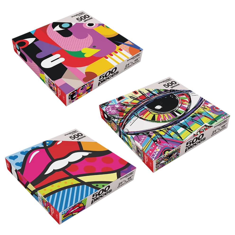 Three colorful 500-piece art puzzles with abstract designs: one features a stylized face, another an eye with vibrant patterns, and the third a geometric design of lips. Each box measures 21\“ x 15\“.