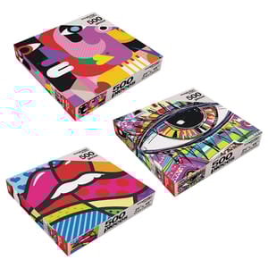 Three colorful 500-piece art puzzles with abstract designs: one features a stylized face, another an eye with vibrant patterns, and the third a geometric design of lips. Each box measures 21\“ x 15\“.