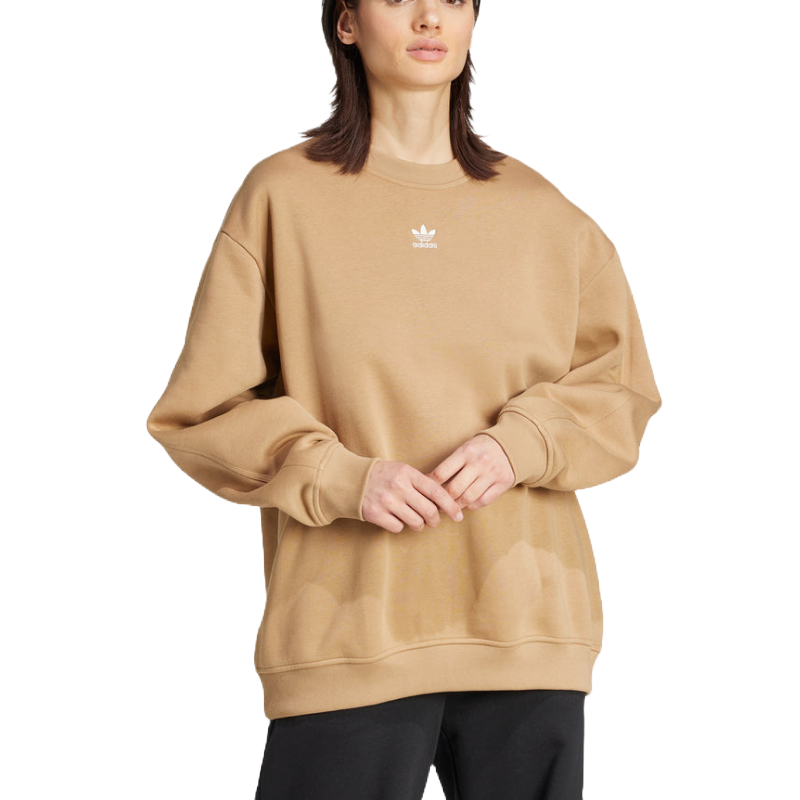 A person is wearing a beige Adidas sweatshirt with a small logo on the chest, paired with black pants.