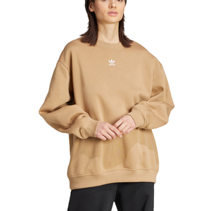 A person is wearing a beige Adidas sweatshirt with a small logo on the chest, paired with black pants.