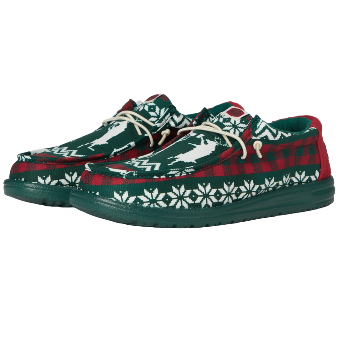 Hey Dude Wally Holiday Cheers Shoes feature a red and green design with white snowflakes and reindeer patterns, resembling a Christmas sweater style. They have white laces and a comfortable, casual build.